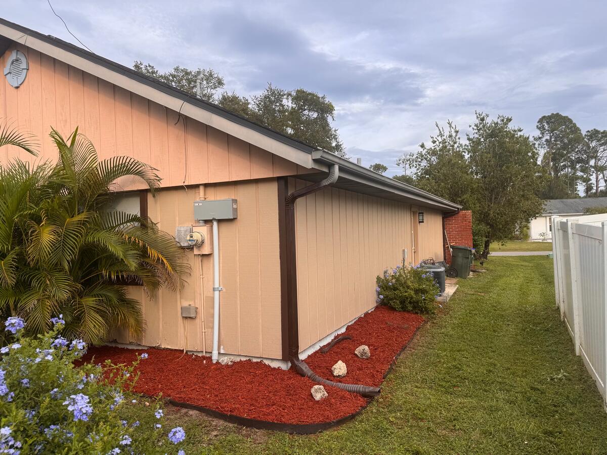 Red mulch bed with edging along the side of a house